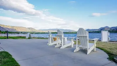 a group of white chairs sitting next to the water at Sandy beach Sauvignon cottage - Osoyoos escapade 3bd-2bt in Osoyoos