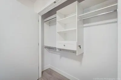 a white closet with white shelves and a door at O Charming Bright Queen Bed Room Ensuite in West Vancouver