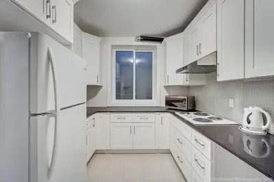 a white kitchen with white cabinets and a white refrigerator at O Charming Bright Queen Bed Room Ensuite in West Vancouver