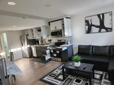 a living room with a black couch and a kitchen at Super luxury suite in Edmonton