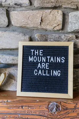 a sign that says the mountains are calling in front of a brick wall at Summit at The Lodges of Canmore in Canmore
