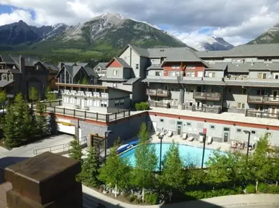 a resort with a swimming pool in front of a mountain at Summit at The Lodges of Canmore in Canmore