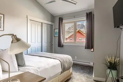 a bedroom with a bed and a window with a house at Mountain Memories Family Fun at The Lodges in Canmore