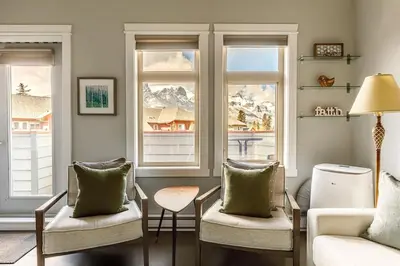 a living room with two chairs and two windows at Mountain Memories Family Fun at The Lodges in Canmore