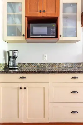 a kitchen with white cabinets and a microwave at Pooches Paradise - Pet Friendly Hot Tub & Pool in Canmore