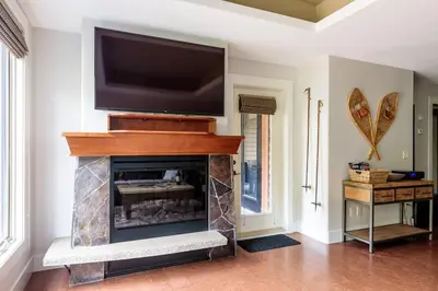a living room with a fireplace with a flat screen tv at Pooches Paradise - Pet Friendly Hot Tub & Pool in Canmore