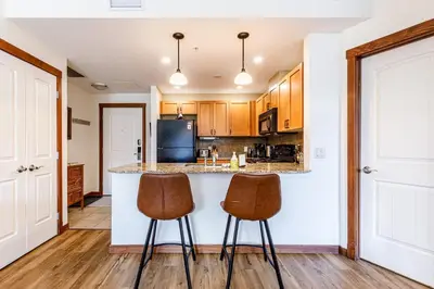 a kitchen with two bar stools at a counter at Mountain Paradise at Falcon Crest Lodge in Canmore