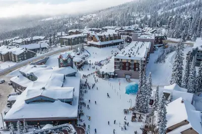 a ski resort in the snow with a group of people at Snow Therapy Chalet - Ski In Out, Hot Tub & Mtn View in Big White