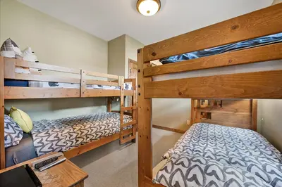 a bedroom with two bunk beds and a desk at Snow Therapy Chalet - Ski In Out, Hot Tub & Mtn View in Big White