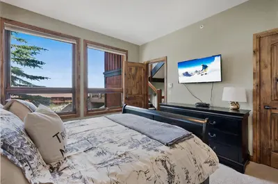a bedroom with a bed and a large window at Snow Therapy Chalet - Ski In Out, Hot Tub & Mtn View in Big White