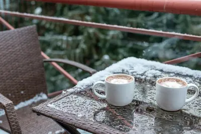 two cups of coffee sitting on a table in the snow at Village Penthouse w Views Pool and Hot Tub in Whistler