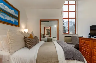 a bedroom with a white bed and a television at Village Penthouse w Views Pool and Hot Tub in Whistler