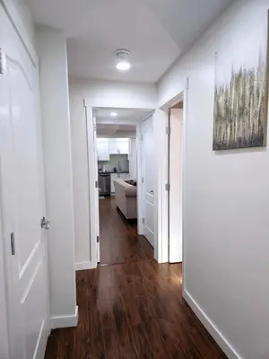 an empty hallway of a apartment with white walls and wood floors at Cozy & Spacious 1-Bedroom SW Calgary near SpruceMeadows in Calgary