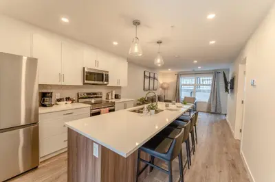 a kitchen with white cabinets and a large island with bar chairs at Skyridge by Canmore Premier in Canmore