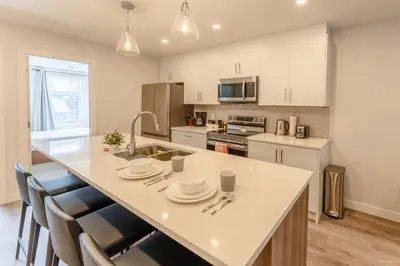 a kitchen with a large white counter top with chairs at Skyridge by Canmore Premier in Canmore