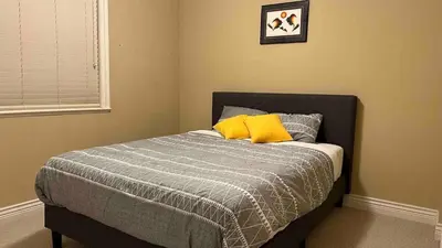 a bedroom with a bed with two yellow pillows at Spacious comfy stay in Richmond