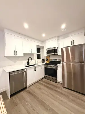 a kitchen with white cabinets and a stainless steel refrigerator at 2bed Lagos House Backyard Suites Downtown in Edmonton