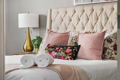 a white bed with pink pillows and a gold lamp at Large Family 4BR w Kid's Play Den! FREE Banff Pass in Calgary