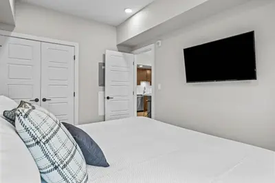 a white bedroom with a bed with a tv on the wall at 2 bedrooms-3 beds 2 baths - Rocky Mountain View Retreat - Heated Pool and Hot Tub in Dead Man's Flats