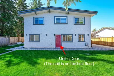 a house with a red door in a yard at Cozy Home with 3BR 4Bath near Richmond Steveston Village in Richmond