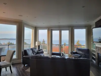a living room with a couch and chairs and windows at Sand and Salt Bed & Breakfast in White Rock
