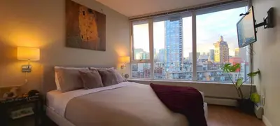 a bedroom with a large bed and a large window at Charming Abode Downtown Vancouver in Vancouver