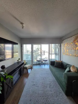 a living room with a green couch and a tv at Charming Abode Downtown Vancouver in Vancouver