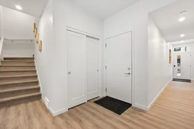 an apartment hallway with white walls and stairs at Luxury 3 Bedrooms Spacious Townhome, 2 Car Garage, Sleeps 8, Heater & AC, King Bed, Easy Ski Access, Next to WinSport, 10km from Calgary Downtown, Near Banff in Calgary