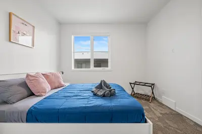 a bedroom with a blue bed and a window at Luxury 3 Bedrooms Spacious Townhome, 2 Car Garage, Sleeps 8, Heater & AC, King Bed, Easy Ski Access, Next to WinSport, 10km from Calgary Downtown, Near Banff in Calgary