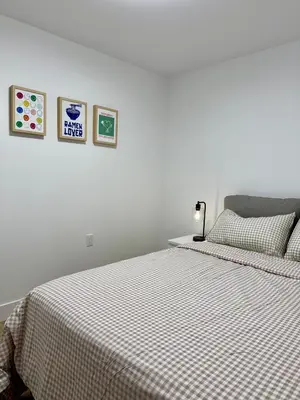 a white bedroom with a bed with a checkered blanket at Levida Living - Cozy 2 Bedroom Suite at the Heart of Langley in Langley