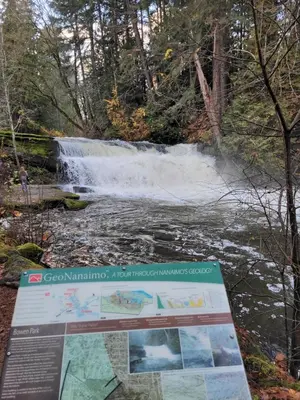 a sign in front of a waterfall in the woods at Campbell Cottage B&B in Nanaimo
