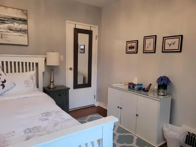 a bedroom with a white bed and a mirror at Campbell Cottage B&B in Nanaimo