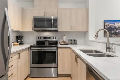 a kitchen with stainless steel appliances and wooden cabinets at Whistler Village Condo Sleeps 7 in Whistler
