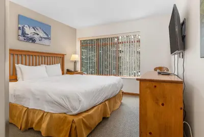 a bedroom with a bed and a television and a window at Whistler Village Condo Sleeps 7 in Whistler