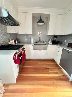 a kitchen with white cabinets and a wooden floor at 3 level, home near downtown! in Vancouver