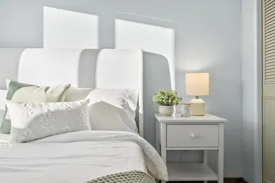 a bedroom with a white bed and a nightstand with a lamp at Silver Springs Family Retreat in Calgary