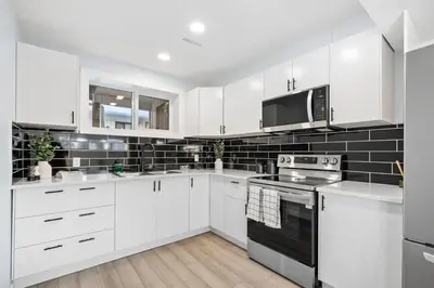 a white kitchen with white cabinets and a microwave at Silver Springs Family Retreat in Calgary