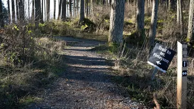 a sign on a dirt trail in the woods at Charming scape by Bear Mountain in Victoria