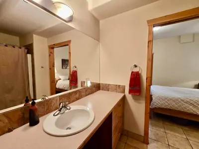a bathroom with a sink and a mirror and a bed at Pika's Place Bed and Breakfast in Canmore