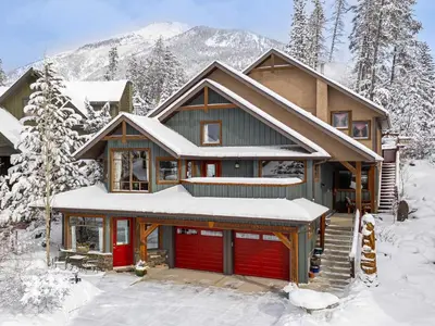 a house with a red garage in the snow at Pika's Place Bed and Breakfast in Canmore