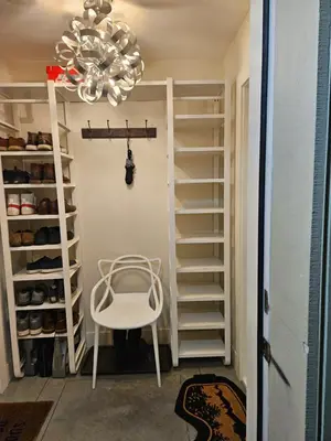 a walk in closet with a white chair and a chandelier at The Ridge in North Vancouver