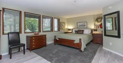 a bedroom with a bed and a chair and windows at Cole's Bay Vacation Retreat Cole's Bay Suite in YYJ