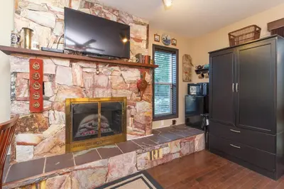 a living room with a stone fireplace with a flat screen tv at Cole's Bay Vacation Retreat Library Room in YYJ