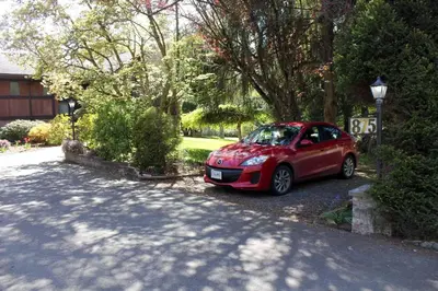 a red car parked on the side of a driveway at Cole's Bay Vacation Retreat Library Room in YYJ