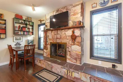a living room with a stone fireplace with a television at Cole's Bay Vacation Retreat Library Room in YYJ