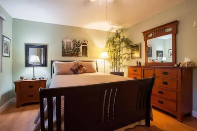 a bedroom with a bed and a dresser and a mirror at Cole's Bay Vacation Retreat Petie's Cottage in YYJ