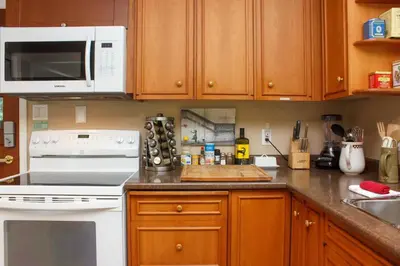 a kitchen with white appliances and wooden cabinets at Cole's Bay Vacation Retreat Petie's Cottage in YYJ