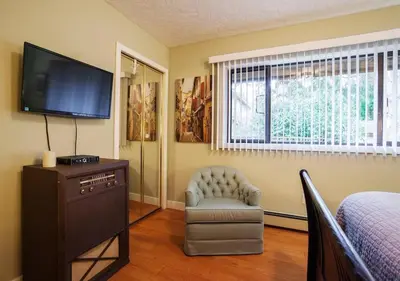a bedroom with a tv and a chair and a bed at Cole's Bay Vacation Retreat Petie's Cottage in YYJ