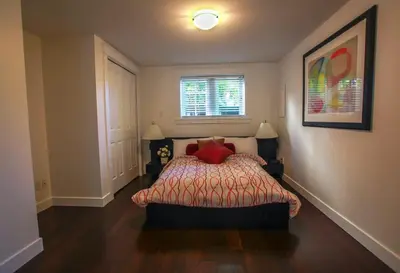 a bedroom with a bed with red pillows and a window at Grand Boulevard Retreat- quiet suite in North Vanc in North Vancouver