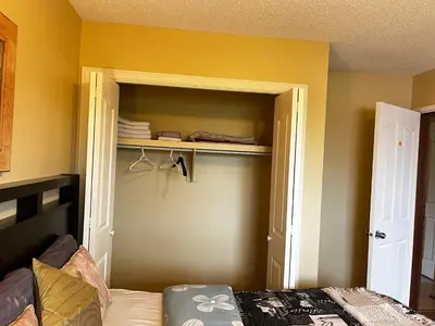 a room with a closet with a bed and yellow walls at Biddington private room close airport! in Calgary